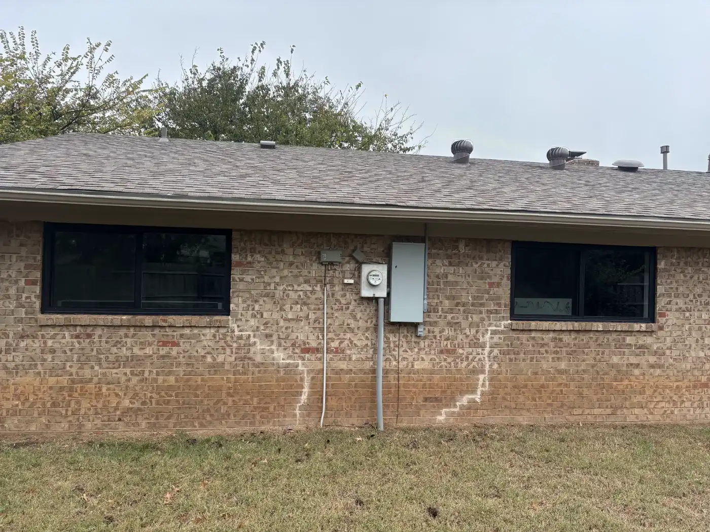 Two new black sliding windows in a tan brick back wall
