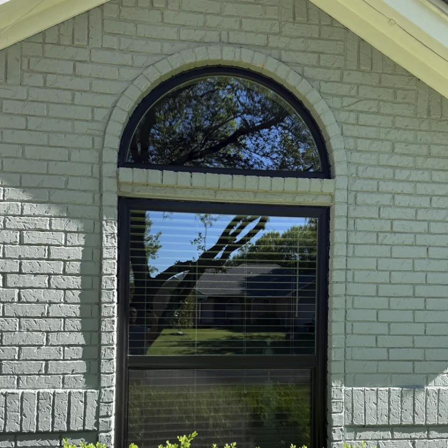The arched window after replacement, with a black frame and no grids