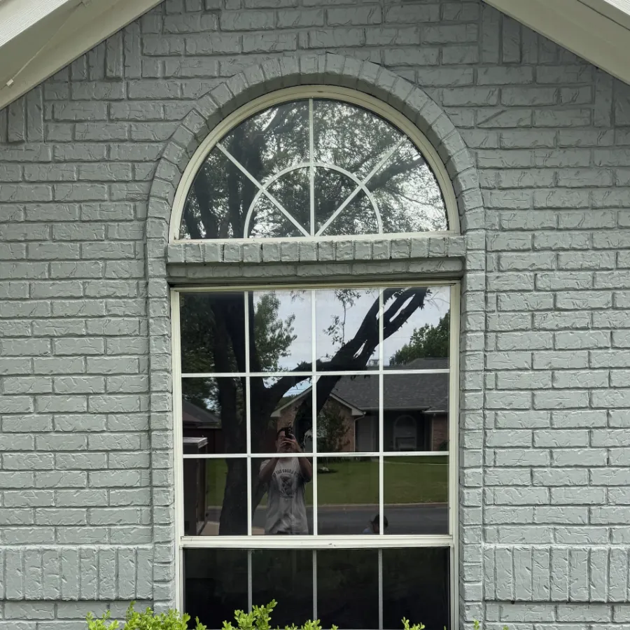The arched window before replacement, with a white frame and grids