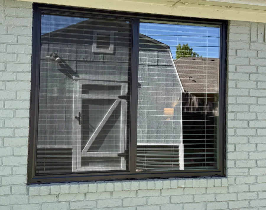 A new dark-framed sliding window in a painted brick wall