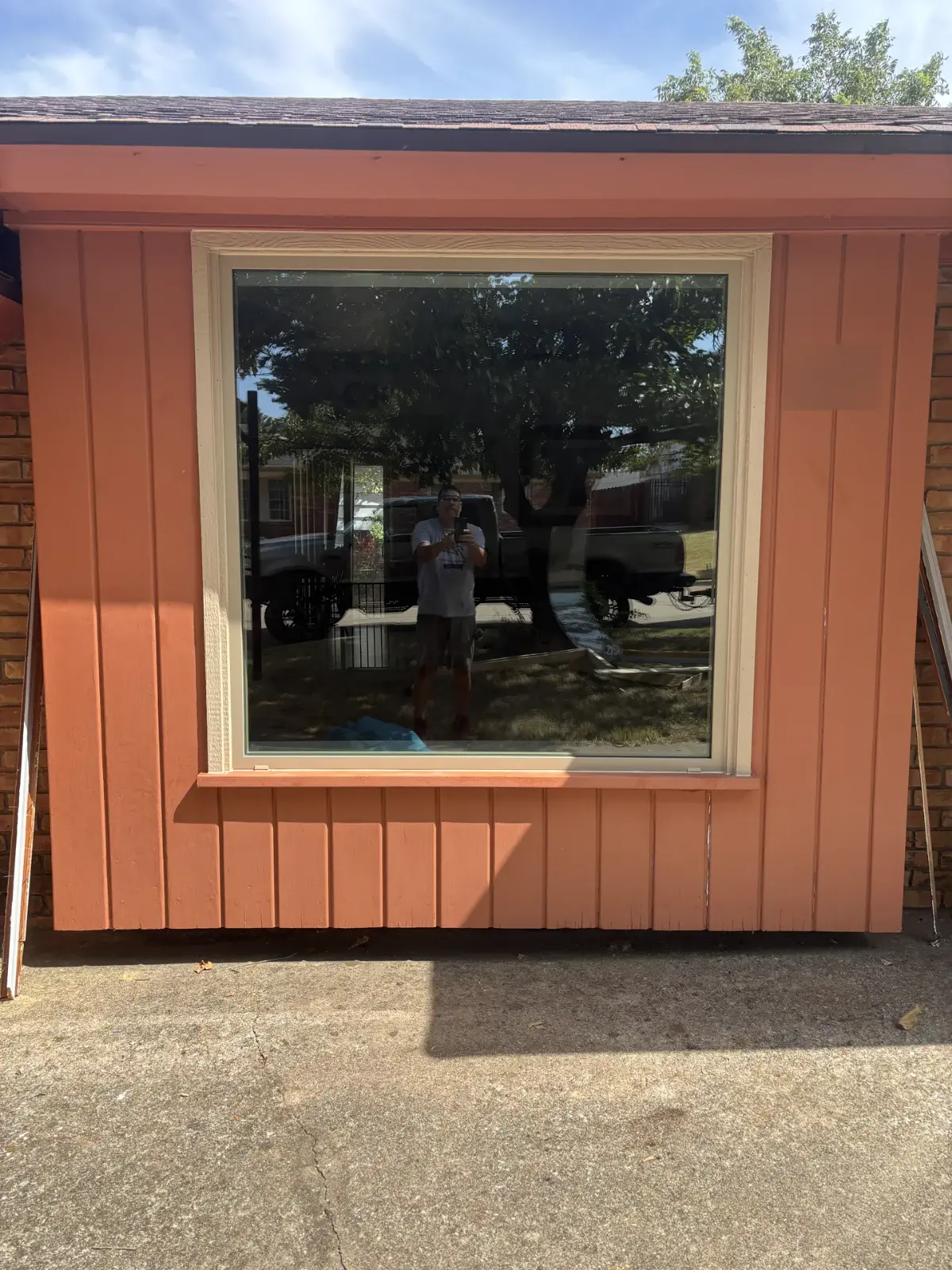 A new picture window with a cream frame in a red board wall, with Louis Rose reflected in the glass